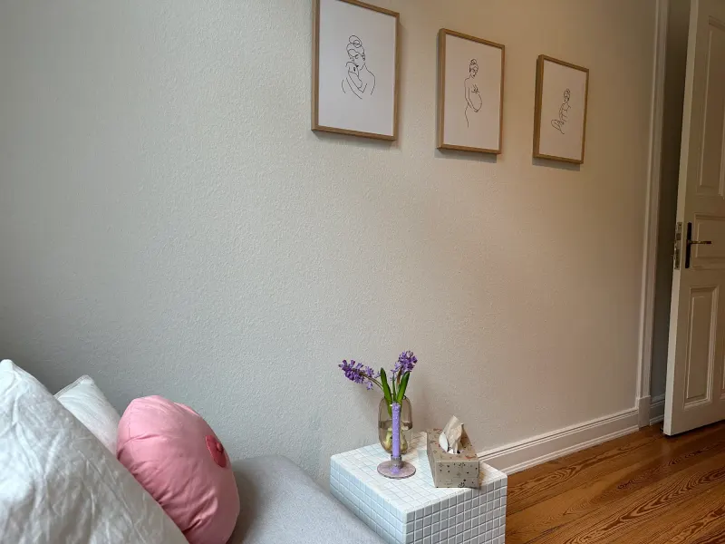 Beratungsraum mit gezeichneten Bildern an der Wand und einem rosa Kissen