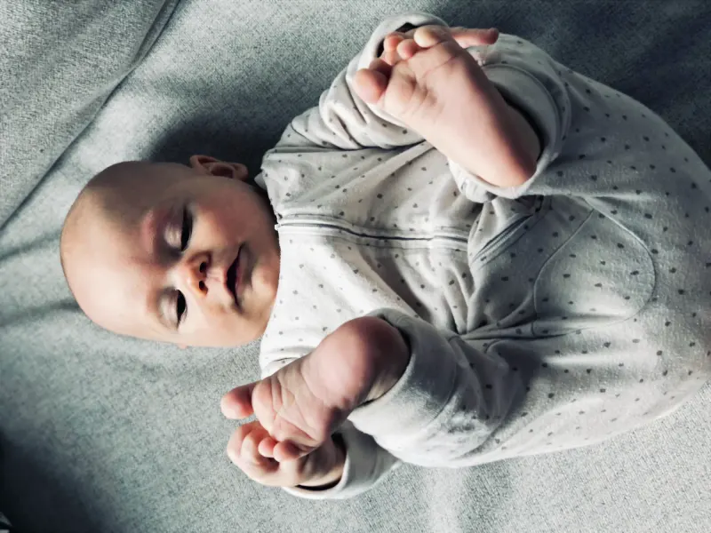 Ein Baby liegt auf einer grauen Decke